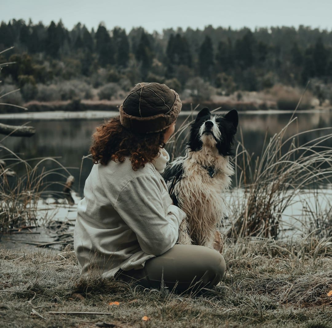 depression support animal — woman in beige jacket sitting beside black and white dog